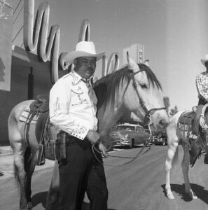 Joe Louis standing beside his horse in front of the Moulin Rouge Hotel and Casino before the Helldorado parade in 1955