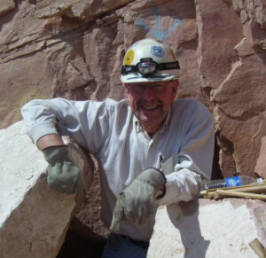 William Durbin on location in front of a rock cliff face with a hard hat and gloves on